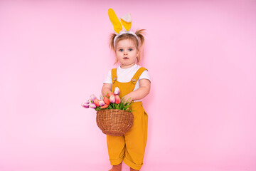 Basket with eggs and flowers in the hands of a surprised girl on a pink background. The concept of spring and Easter