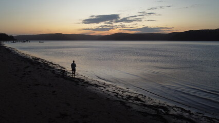 Naklejka premium man contemplating the sunset on the beach
