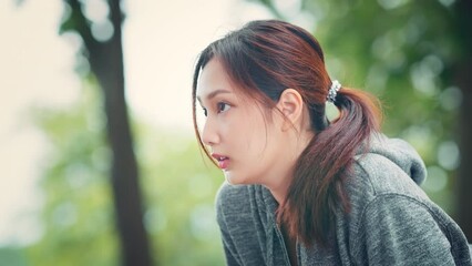 Young asian woman resting after running in the road at the park after a daily exercise, running jogging for his fitness in the warm summer morning.