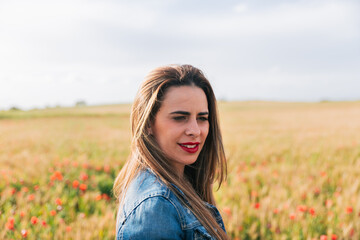 Portrait of young woman in denim jacket on flower meadow background.