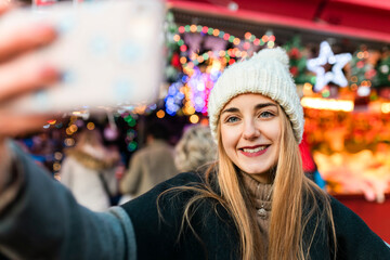 Young woman taking selfie on Christmas market