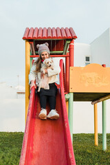 Smiling female with dog sliding in playground
