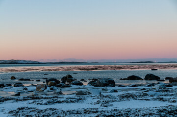 Landscape shot highlighting the rugged mountains and snow-covered beaches of arctic norway during a brief golden hour during the long winters.