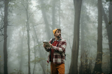 Active man hiking in nature. Hipster dressed man exploring a cold mountain and looking aside