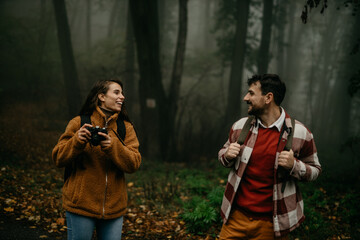People hiking - happy hiker couple trekking as part of healthy lifestyle outdoors activity. Young smiling couple walking in nature on a cold day