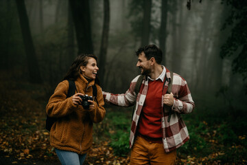 People hiking - happy hiker couple trekking as part of healthy lifestyle outdoors activity. Young multiracial couple walking in nature on a cold day