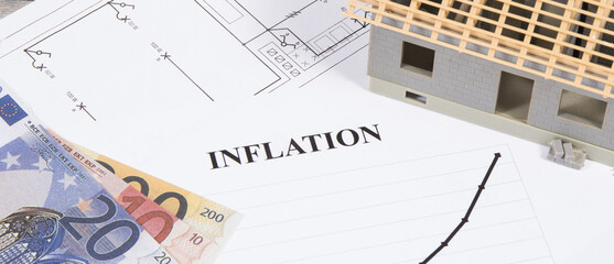 Inscription inflation, currencies Euro, toy house under construction and construction drawings. High prices of real estate, building or rent home