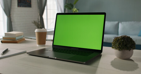 Modern laptop with mock up chroma key green screen st on desk of living room. The only template you need - remote work concept close up