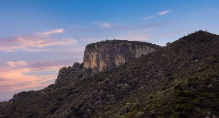 Fototapeta na wymiar Rocky Mountain by the Sea Coast. Colorful Twilight Sky Art Render. Sardinia, Italy. Nature Background
