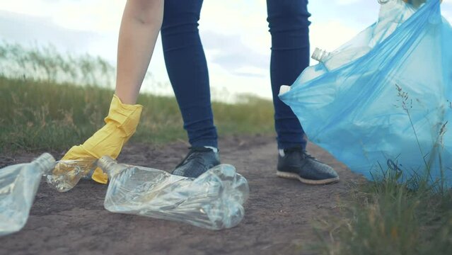 volunteer collects plastic trash in the park. recycle plastic bottle clean cleanup ecology concept blurred background. girl volunteer gloves collects plastic bottles and glasses in a trash bag