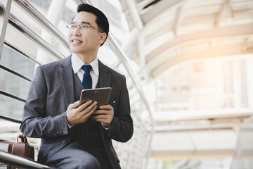 Handsome asian businessman holding digital tablet, wear suit and eyeglasses. Leadership executive...