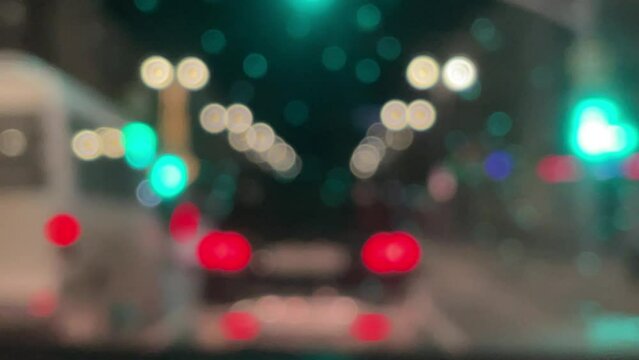 Blurred car lights bokeh in the evening city. Defocused headlights and street lighting at night. Moving bokeh circles of cars at night. Blurred city traffic background