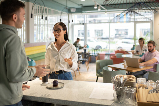 Woman chatting with barista in cafe