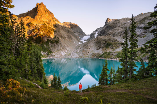 Female In Red Jacket Next To Gorgeous Blue Alpine Lake At Sunset