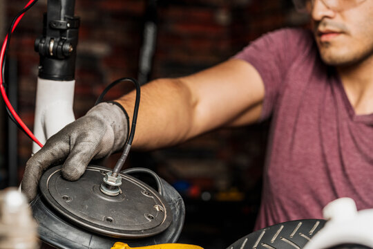 A mechanic installing the wheel rim on the tire of an electric scooter