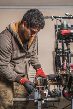 A mechanic repairing a fender of an electric scooter on a table