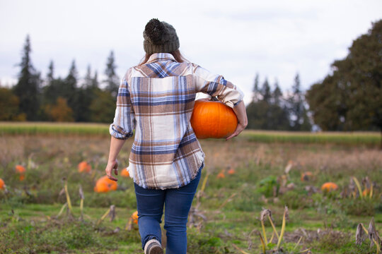 A woman holding a pumpkin in a pumpkin patch