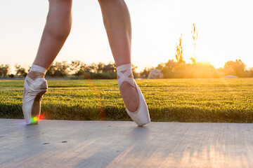 Feet of ballet dancer in pointe shoes at sunset with rainbow