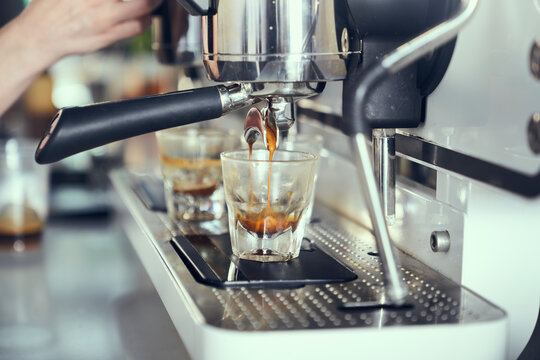 An espresso shot is pulled into a shot glass from a machine.