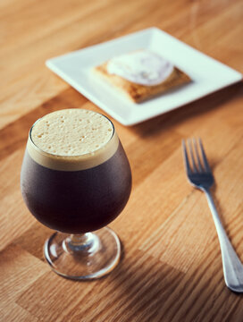 A nitro cold brew served with breakfast pastry.