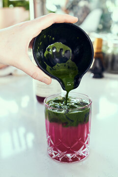 A Hand Pours Matcha Green Tea Into Prickly Pear Lemonade.