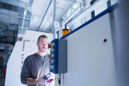 Young male engineer examining control panel with multimeter in an industrial plant, Freiburg im Breisgau, Baden-W&uuml;rttemberg, Germany