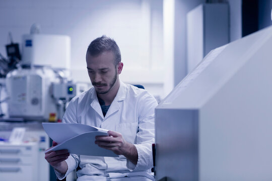 Young Male Scientist Looking At Report In An Optical Laboratory, Freiburg Im Breisgau, Baden-Württemberg, Germany