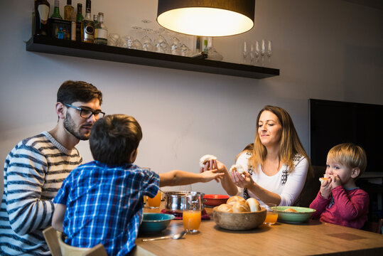 Mother is offering bread to her son while family watches, Munich, Germany