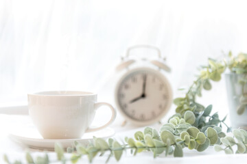 Obraz na płótnie Canvas Select focus. Coffee morning. White steaming cup of hot coffee for relax after wake up, vintage alarm clock background. Lifestyle Concept