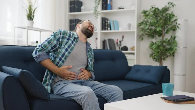 Middle-aged man suffering from stomach ache at home, severe food poisoning