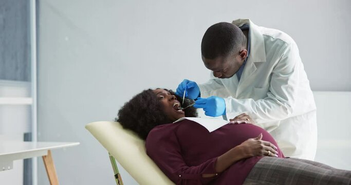 Dentist Treating Teeth Of Young Pregnant Woman Patient Lying