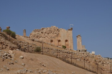 Sunny temples, arches, the Nymphaeum, stone ornaments, columns and column bases on the ruins of the city of Jerash in Jordan.