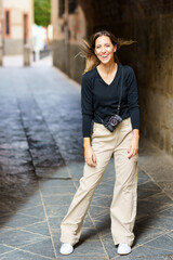 Confident young female traveler smiling happily on street