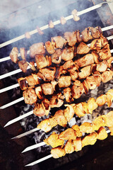 Selective focus. Cooking barbecue on the mangal in nature. Grilled tasty meet cooking on the party. Traditional Russian shashlik on a barbecue skewer on sunny forest.