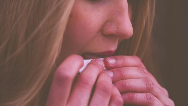 Close-up of woman licking cigarette rolling paper