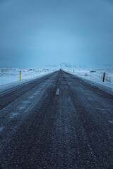 Iceland winter road street to the mountain with snow and misty blue sky 