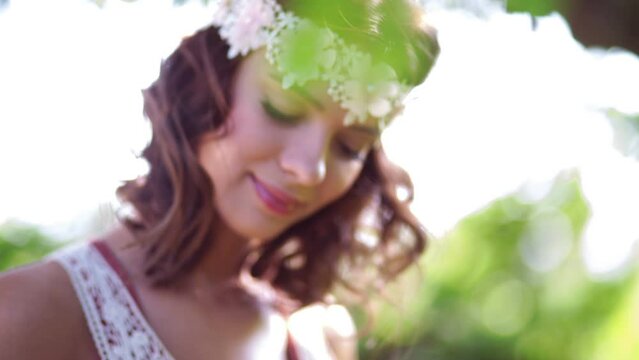 Dreamy hippie girl in a vintage white lace headband holding a small bouquet of wild flowers standing in nature looking away thoughtfully