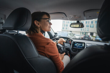Fototapeta na wymiar Adult caucasian businesswoman in glasses driving a car