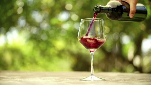 Red wine being filled into glass in slow motion on outdoor table