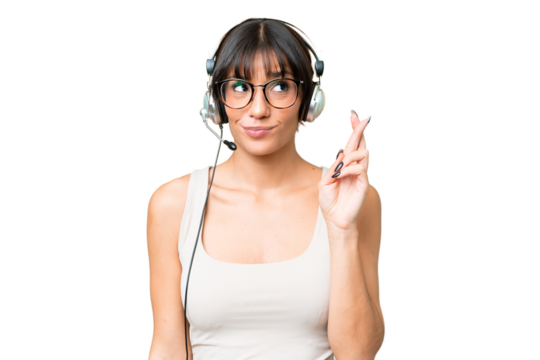 Telemarketer caucasian woman working with a headset over isolated background with fingers crossing and wishing the best