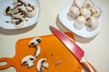 Still life with raw food, preparations for the winter, a plate and an orange board with chopped mushrooms