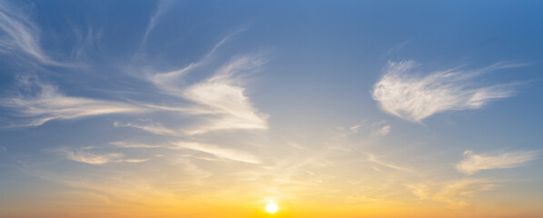 The yellow sun and white smooth cirrus clouds on blue sky, nature panorama background.