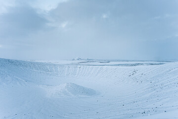 Iceland snow covered vulcanic crater in winter with clouds over white landscape