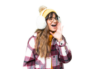 Young caucasian woman wearing winter muffs over isolated chroma key background shouting with mouth wide open to the lateral