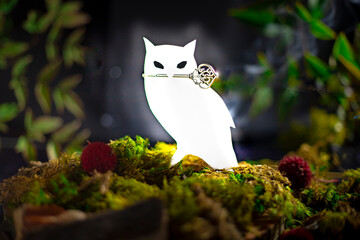 Glowing white owl with a key in its beak, magical still life set in the woods.