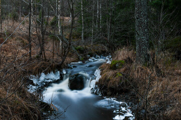Rapidly flowing water in a stream in the nature in Finland in winter