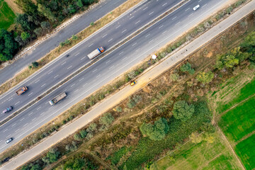 aerial drone decending shot flying over yellow and green mustard feilds with busy 6 lane highway in...
