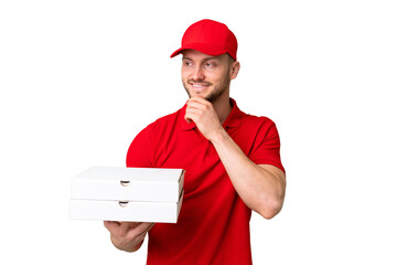 Pizza delivery man with work uniform picking up pizza boxes over isolated chroma key background looking to the side and smiling