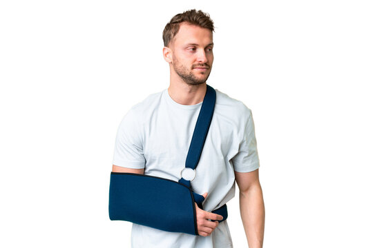 Young Caucasian Man With Broken Arm And Wearing A Sling Over Isolated Chroma Key Background Looking To The Side