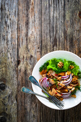 Marinated herrings with delicacies, walnuts and fresh vegetable leaves on wooden table
